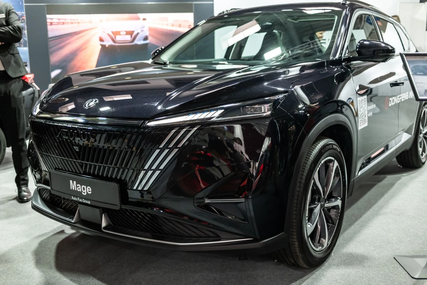 Czarny samochód wystawowy o nowoczesnym wyglądzie, prezentowany w salonie lub na targach motoryzacyjnych. Auto ma elegancką, aerodynamiczną sylwetkę oraz dobrze widoczne szczegóły przedniego grilla i reflektorów.