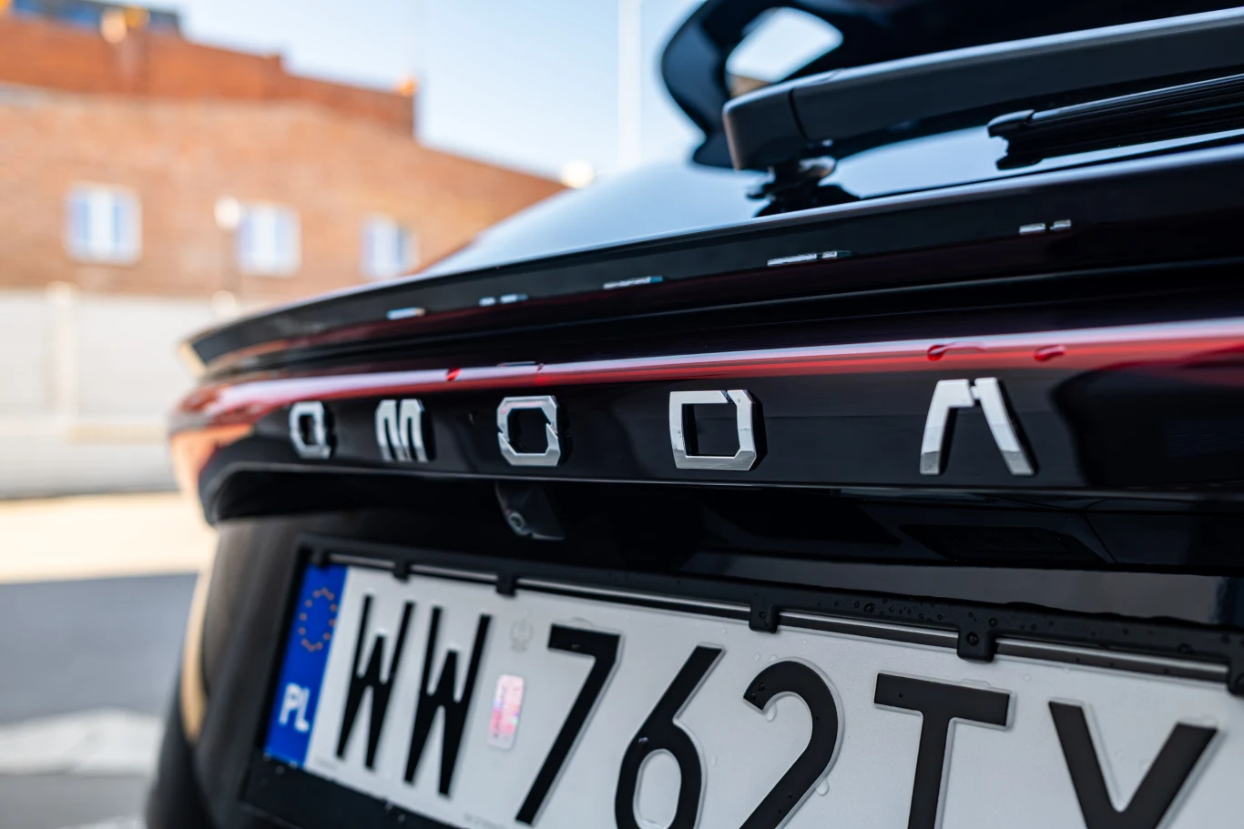 Widoczny tył samochodu marki OMODA z polską tablicą rejestracyjną. Detale obejmują oznaczenie modelu oraz tablicę rejestracyjną z literami 'WW 762TY'.