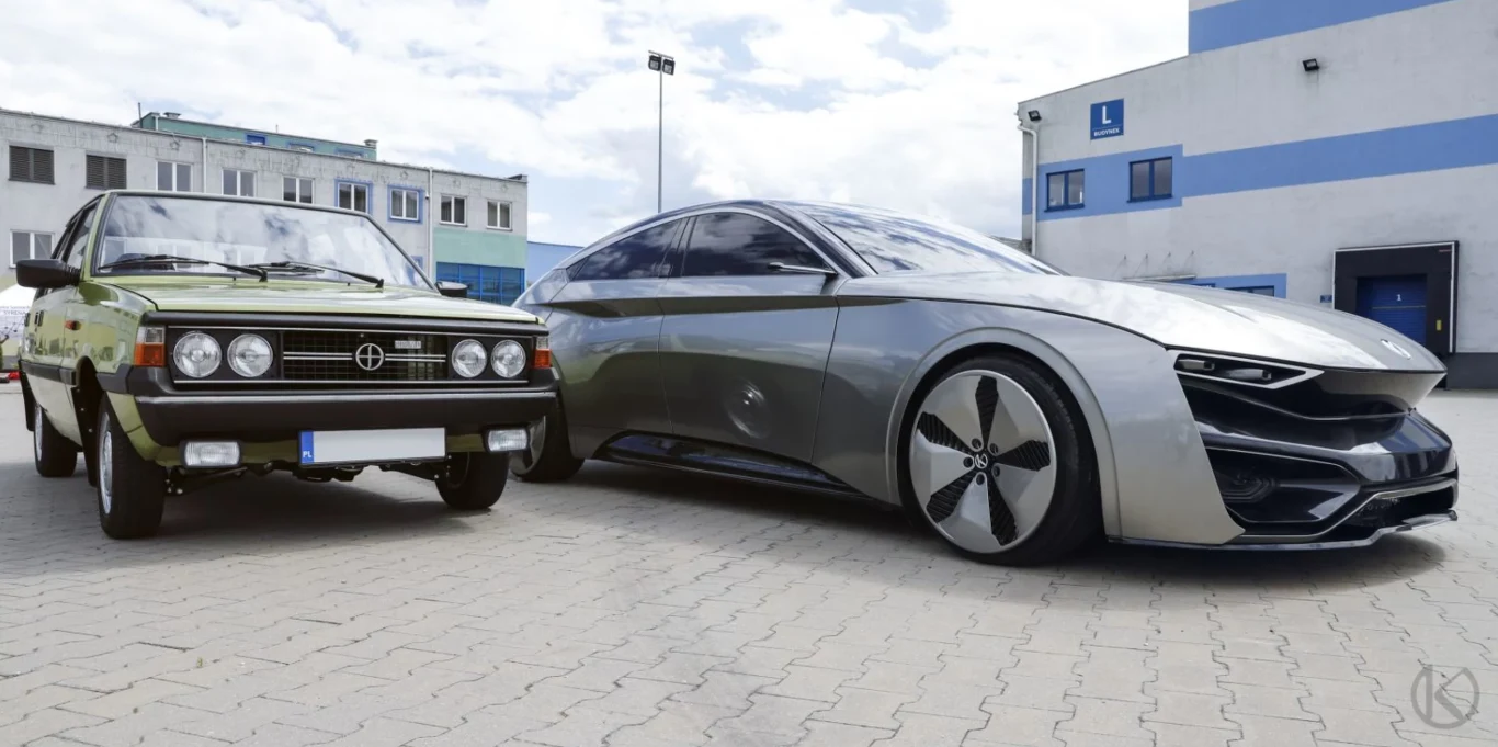 Dwa samochody zaparkowane obok siebie na tle nowoczesnego budynku. Po lewej stronie znajduje się starszy model o zielonym kolorze z klasycznymi reflektorami, a po prawej nowoczesny, futurystyczny pojazd z aerodynamiczną sylwetką i dużymi felgami.