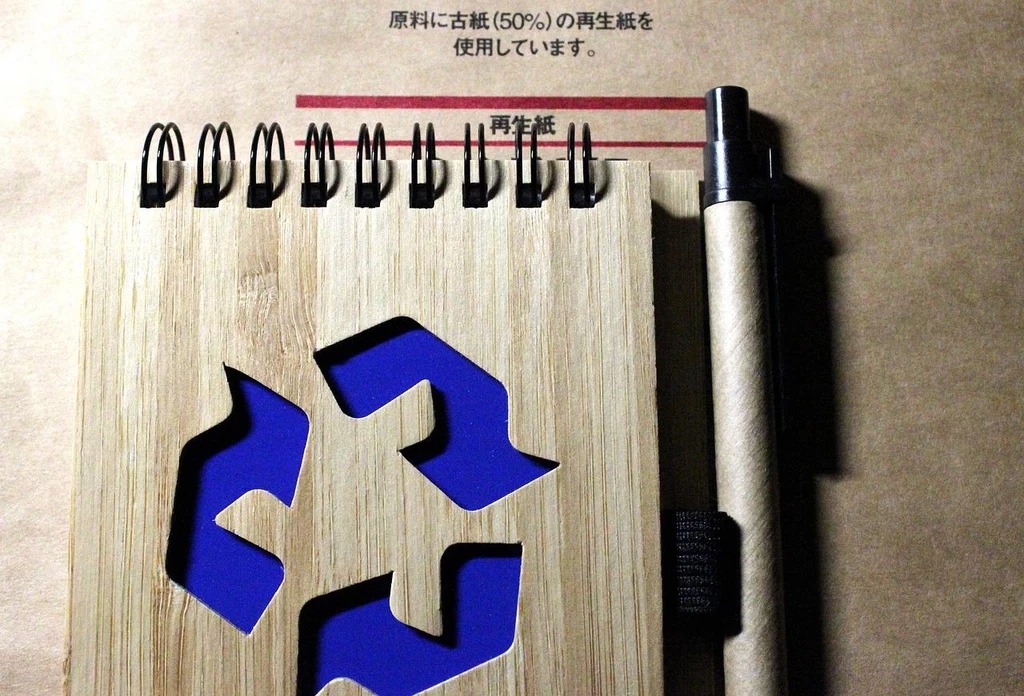 Fot. pixabay.com/ Henry_Wang Notes bambusowy z wyciętym symbolem recyklingu, długopisem i tekstem w języku japońskim na tle z ekologicznego papieru.