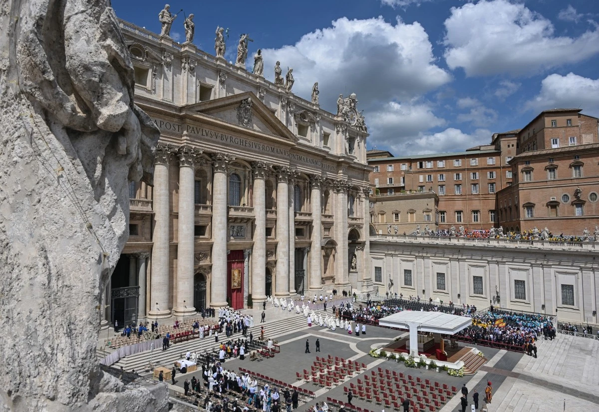 Pogrzeb papieża Franciszka. Kto zapłacił za podróż polskiej delegacji do Watykanu? Dostojna fasada Bazyliki św. Piotra w Watykanie otoczonej wiernymi zgromadzonymi na placu, z widocznymi rzędami krzeseł i podium przygotowanym do uroczystości religijnej. Z tyłu widać zamglone niebo z chmurami.