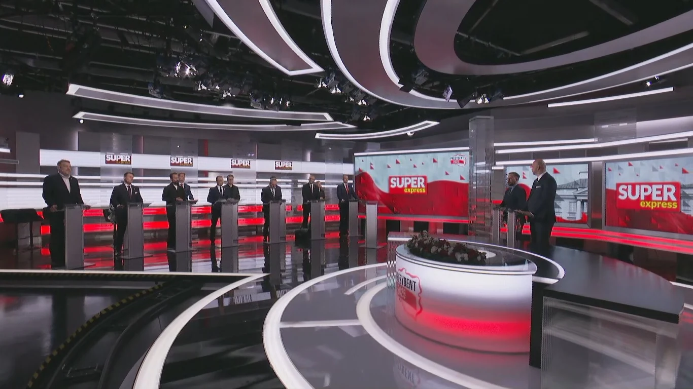 Rosyjskie media o debacie wyborczej. Wskazują na dwóch kandydatów Debata polityczna w nowoczesnym studiu telewizyjnym z udziałem kilku osób stojących za mównicami. W tle widoczne loga stacji telewizyjnej 'Super Express'. Jasne oświetlenie i futurystyczny wystrój studia.