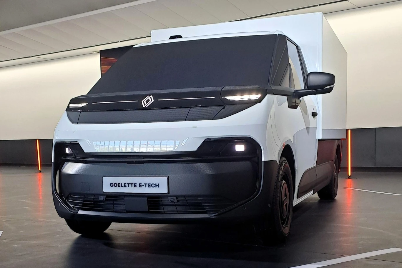 Biały samochód dostawczy Goelett E-Tech zaparkowany w nowoczesnym wnętrzu. Design pojazdu jest nowoczesny i futurystyczny, z gładkimi liniami i ciemnym przodem.