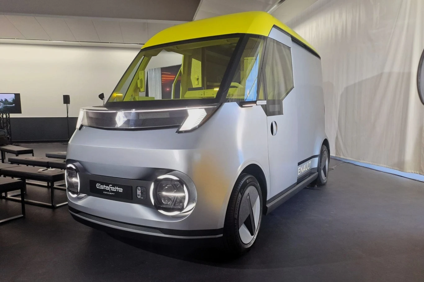 Nowoczesny, futurystyczny pojazd z logo ElektraFahre widoczny w dobrze oświetlonym pomieszczeniu wystawowym. Samochód ma srebrne nadwozie i żółty dach, co nadaje mu unikatowego wyglądu modernistycznego.