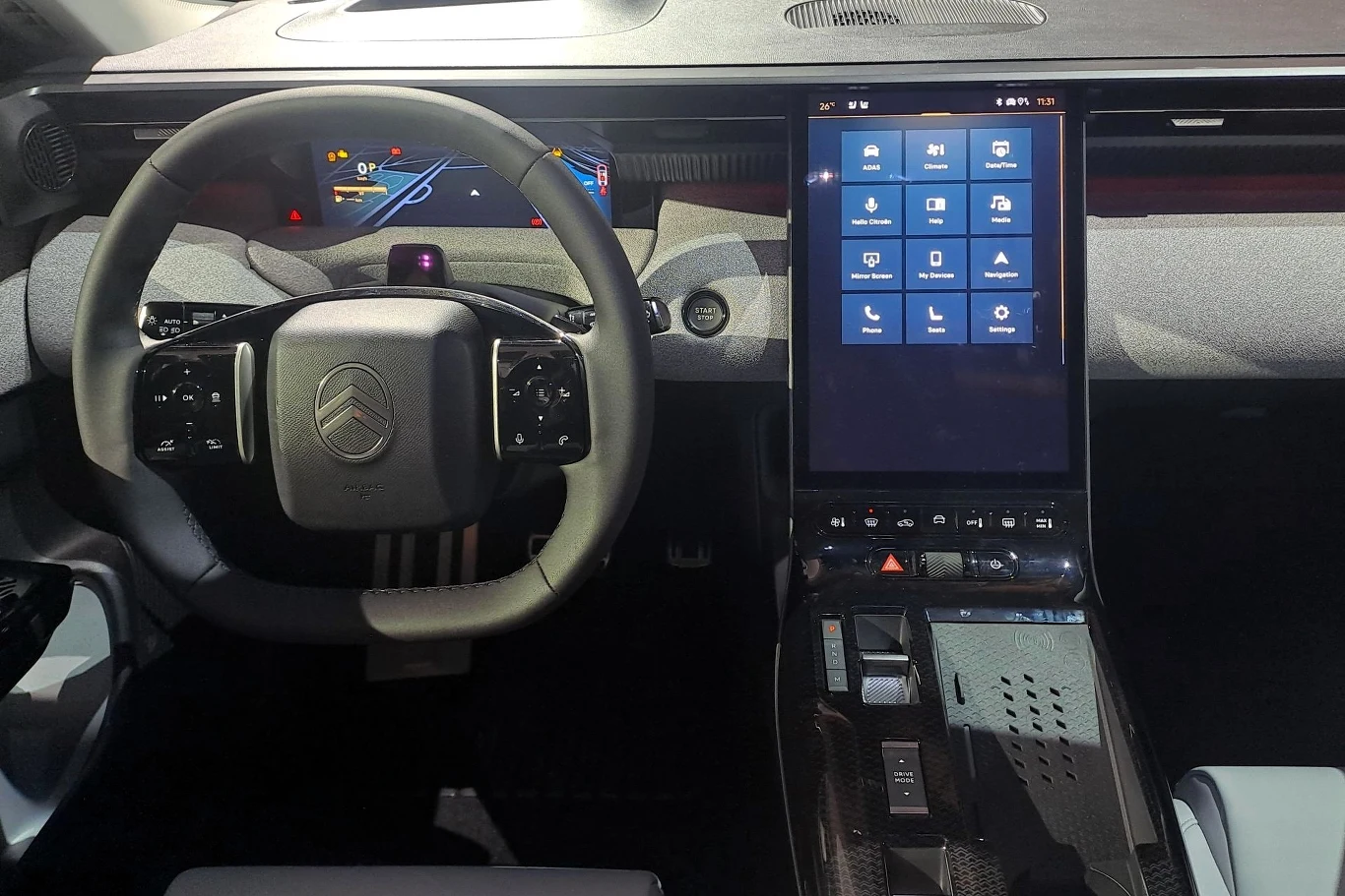 Wnętrze Citroena z nowoczesnym kokpitem: kierownica z logo Citroena, cyfrowy wyświetlacz oraz duży pionowy ekran dotykowy. Deska rozdzielcza ma minimalistyczny design, z widocznymi nowoczesnymi technologiami.