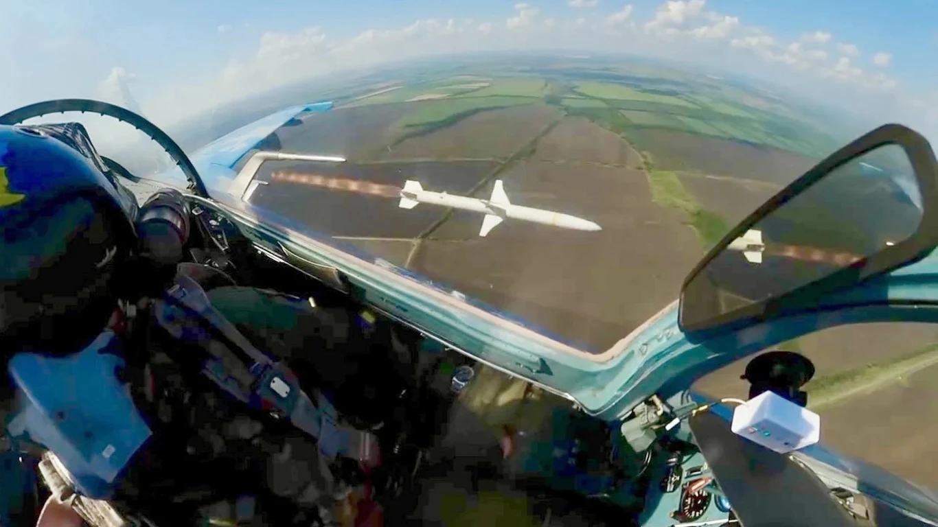 MiG-29 w spektakularny sposób zestrzelił drona Kokpit myśliwca w trakcie lotu nad polami, widoczny pilot w hełmie patrząc na krajobraz, z wyrzutnią pocisków. W tle rozciągają się pola i zielone obszary.