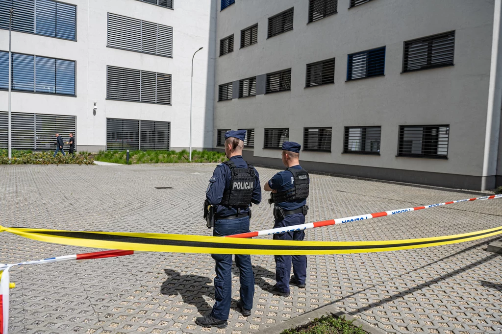 Do ataku doszło we wtorek rano Dwóch policjantów w kamizelkach, stojących na tle budynku. Przestrzeń oddzielona jest taśmą policyjną. Jasno otynkowany budynek z zamkniętymi oknami w tle.