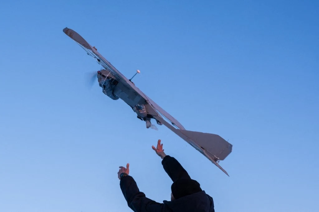 Drony zaatakowały Krym. Wybuchy w pobliżu lotnisk wojskowych Dron w locie nad błękitnym niebem z wyciągniętymi do niego rękoma osoby na pierwszym planie.