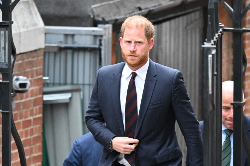 Książę Harry przegrał w sądzie. Poszło o policyjną ochronę Mężczyzna w eleganckim garniturze idzie przez bramę, patrząc przed siebie. Za nim widoczna jest ceglana ściana i fragment metalowego ogrodzenia. Całość sprawia wrażenie formalnego otoczenia.