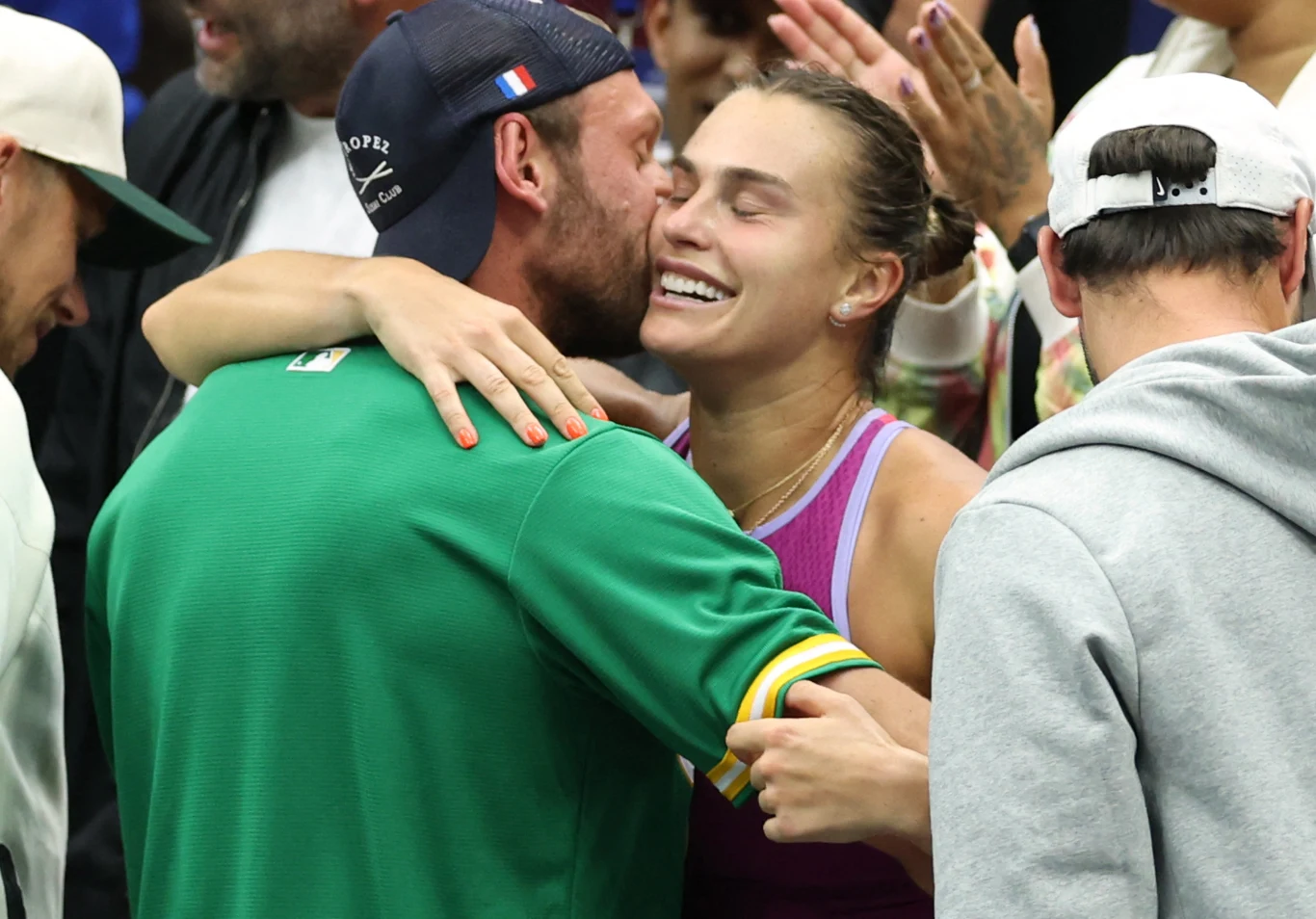 Aryna Sabalenka i Georgios Frangulis Aryna Sabalenka i Georgios Frangulis razem, kobieta w stroju sportowym, mężczyzna w zielonej kurtce, wokół inni ludzie.