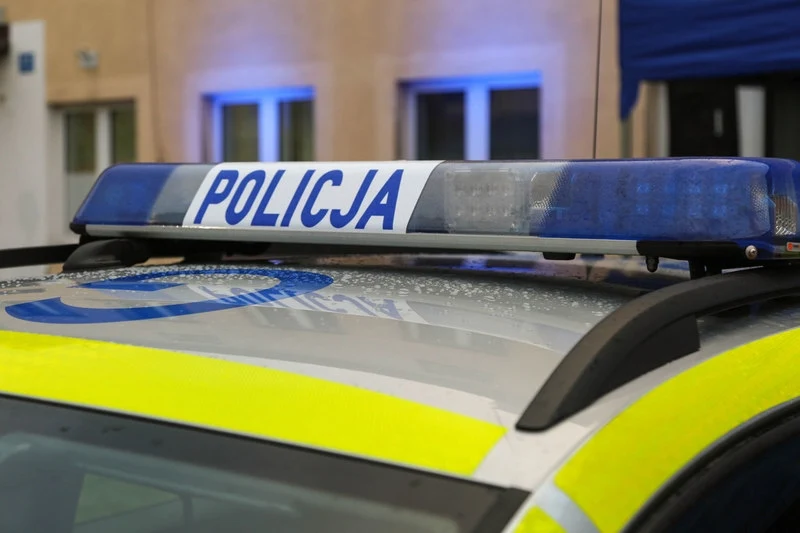 Policyjny pościg w Małopolsce. Motocyklista trafił do szpitala Niebiesko-biały napis 'POLICJA' na sygnalizacji świetlnej zamontowanej na dachu policyjnego radiowozu. Tło stanowi fasada budynku z widocznymi oknami.
