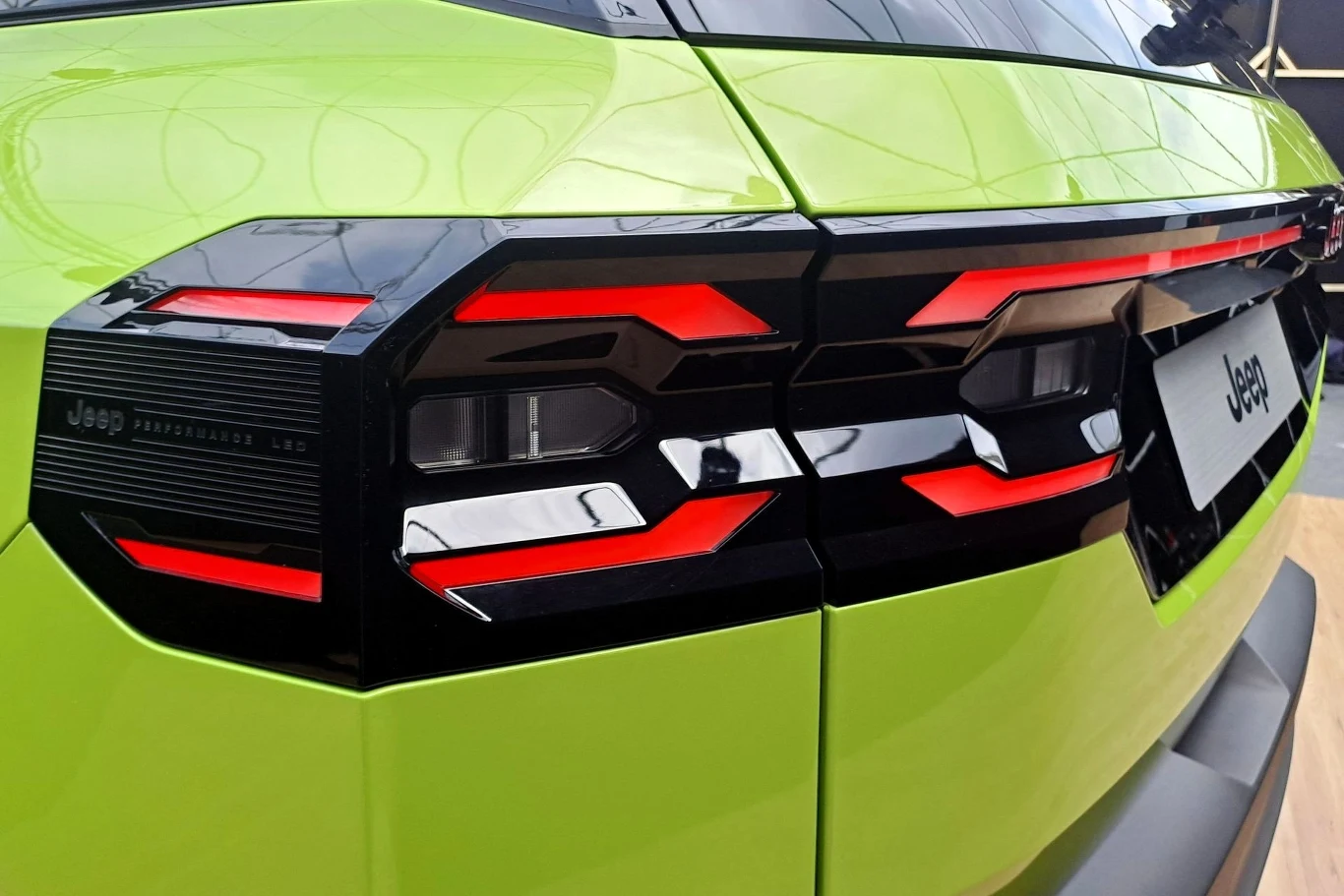 Jasnozielony samochód marki Jeep, skupienie na nowoczesnych tylne reflektory z charakterystycznym czerwonym i czarnym wzorem. Stylowe i futurystyczne wykończenie karoserii.