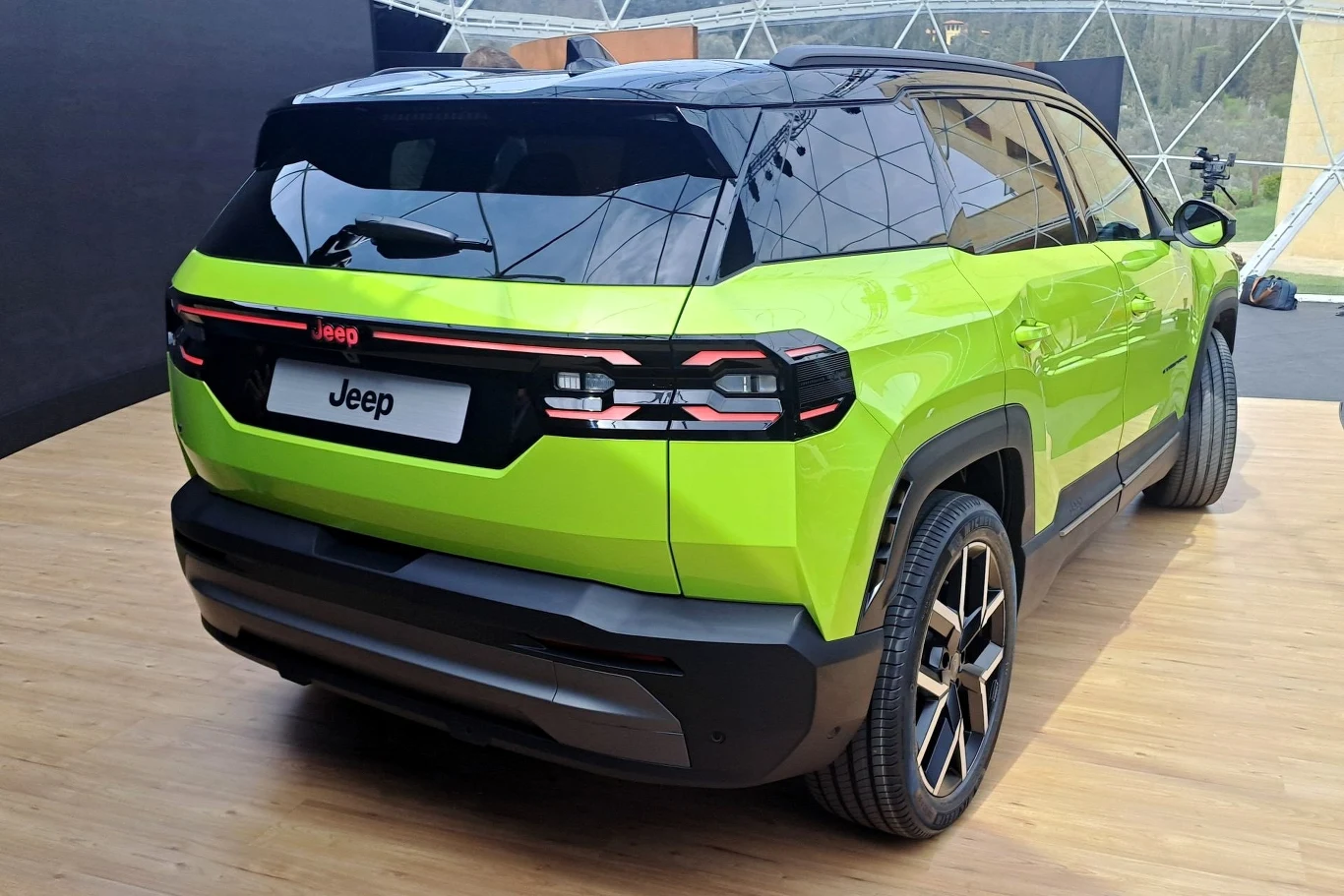 Nowoczesny samochód terenowy w jaskrawej zieleni, zaprezentowany w przestronnym, dobrze oświetlonym pomieszczeniu. Wyróżnia się charakterystycznym wzornictwem tylnych świateł i eleganckimi felgami.