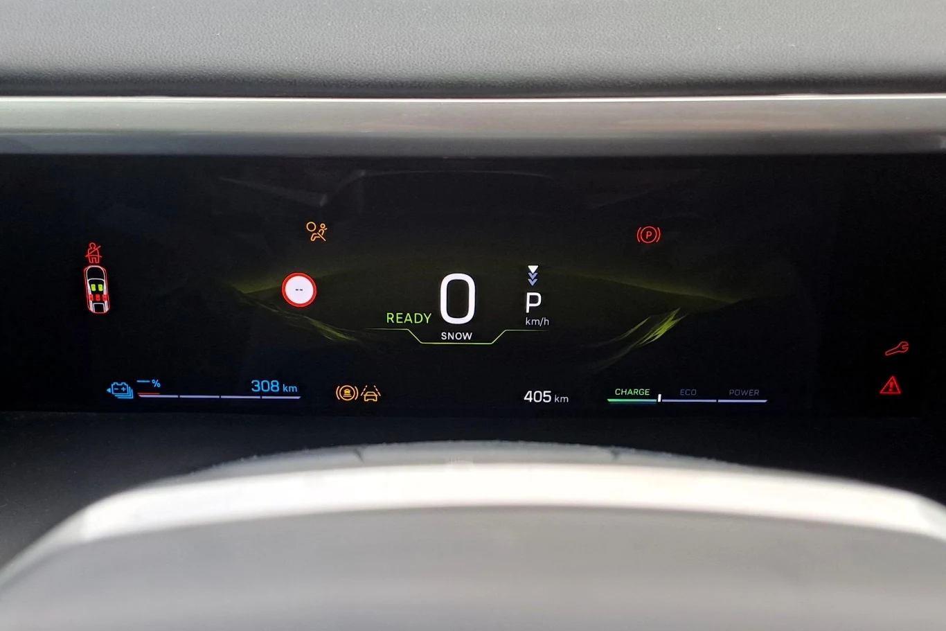 Nowoczesna cyfrowa tablica wskaźników w samochodzie elektrycznym wyświetlająca aktualną prędkość, poziom naładowania baterii, oraz inne istotne wskaźniki i kontrolki dotyczące statusu pojazdu.