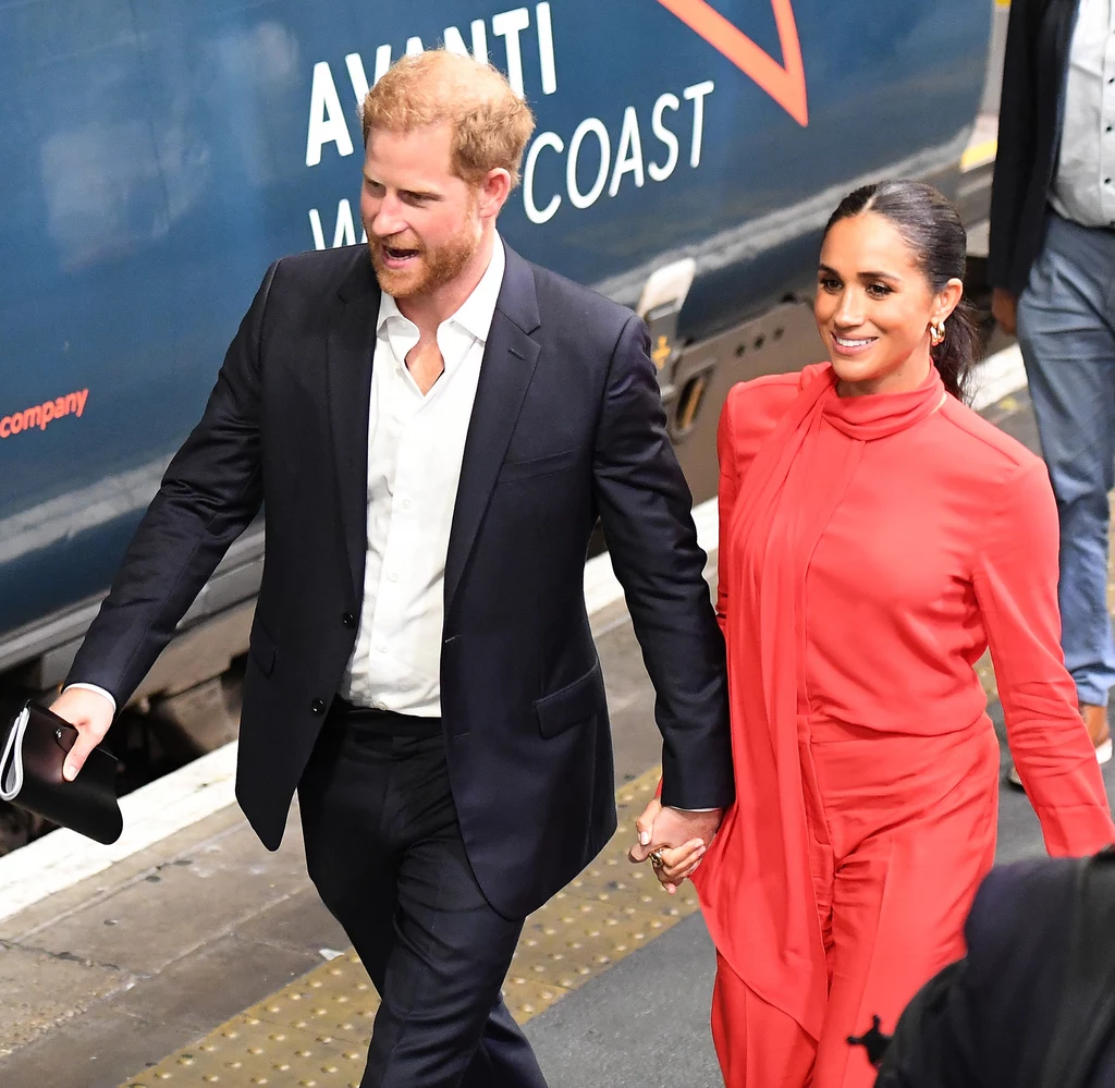 Amerykańskie media spekulowały, że na Met Gali 2025 mogą pojawić się książę Harry i Meghan Markle Para trzymająca się za ręce na peronie kolejowym, mężczyzna w ciemnym garniturze, kobieta w czerwonej sukni.