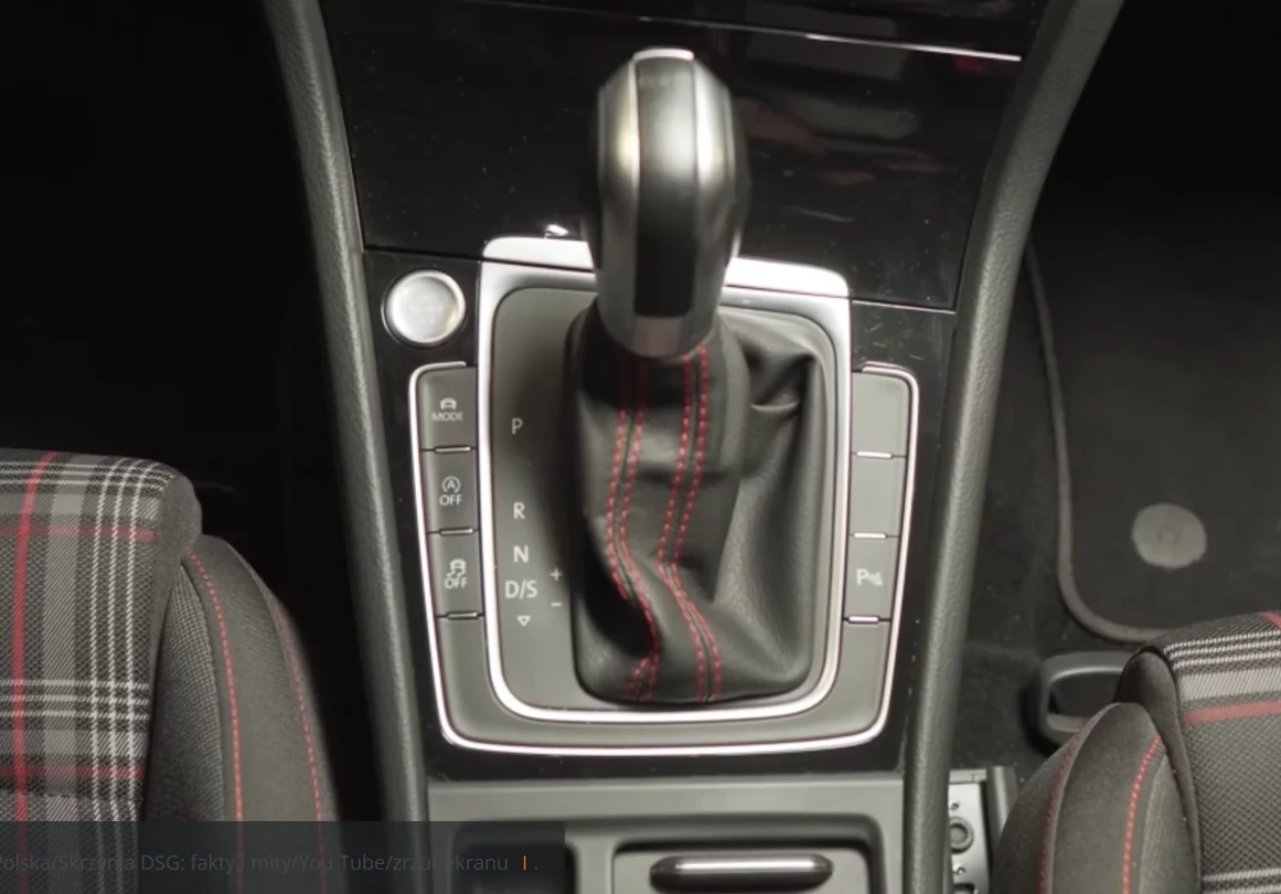 Co psuje się w skrzyni DSG? Automatyczna skrzynia biegów w samochodzie, wykonana z ciemnych materiałów, z widocznym czerwonym przeszyciem na gałce zmiany biegów.