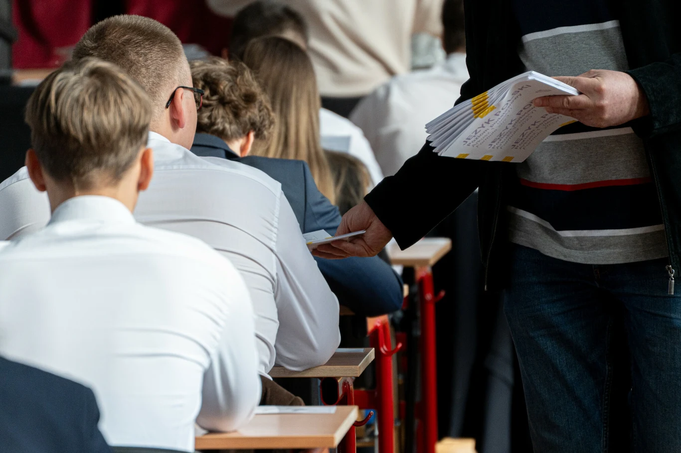 W jakich sytuacjach następuje unieważnienie matury? Uczniowie na egzaminie maturalnym, nauczyciel rozdaje arkusze w klasie