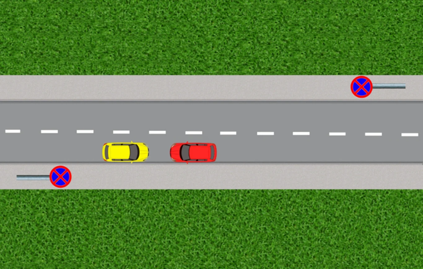 Widok z góry na dwujezdniową drogę, po której jedzie żółty i czerwony samochód obok siebie. Po bokach drogi są znaki zakazu zatrzymywania się i postoju.