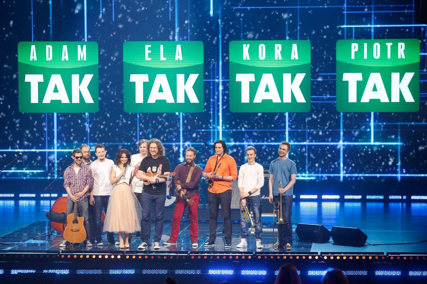 Kraków Street Band w 2014 r. dotarł do finału programu "Must Be The Music" w Polsacie Grupa uczestników programu rozrywkowego na scenie, za nimi duże napisy z imionami 'Adam, Ela, Kora, Piotr' oraz słowem 'TAK'. Wszyscy wyglądają na uśmiechniętych i zadowolonych.