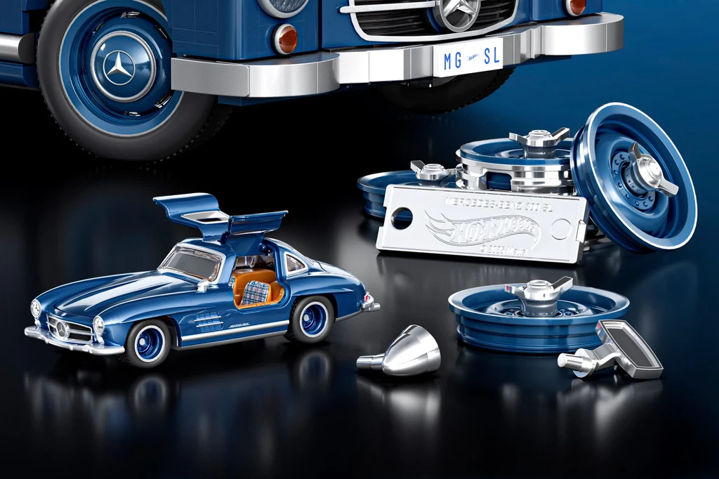 Do każdego modelu dołączony jest resorak 1:64 i dodatkowe elementy do modyfikacji wyglądu Model samochodu Mercedes-Benz z otwieranymi drzwiami, widoczny na tle kół i innych części samochodowych. Dominują niebieskie i srebrne kolory, co podkreśla elegancję i styl pojazdu.