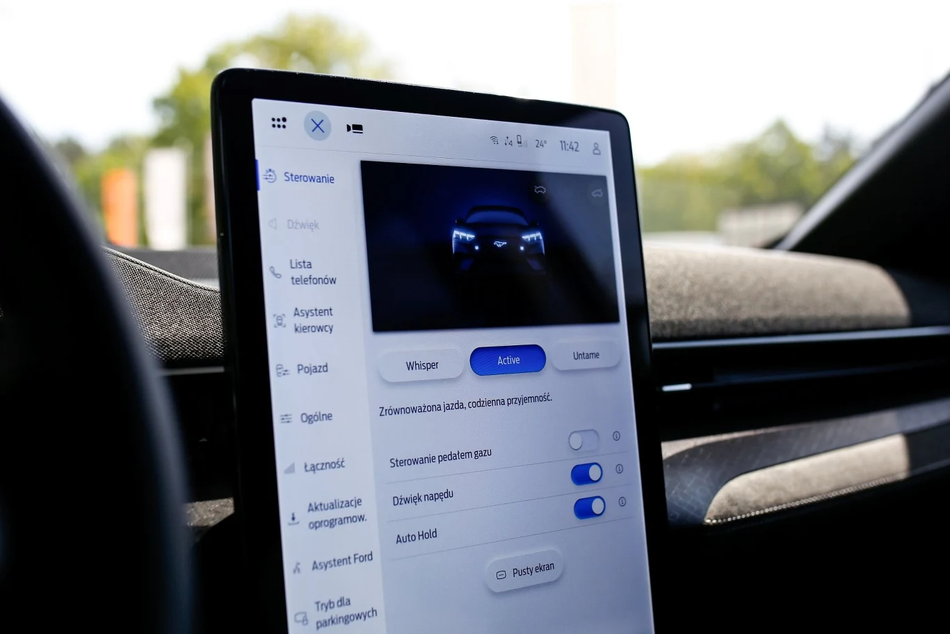 Ekran dotykowy w samochodzie z panelem ustawień pokazujący różne opcje sterowania. Ekran jest nowoczesny, osadzony w desce rozdzielczej z widokiem na ustawienia dla asystenta jazdy oraz innych funkcji pojazdu.