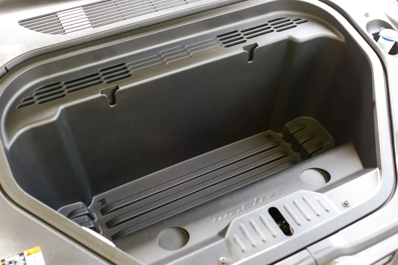 Przestronny bagażnik przedni samochodu elektrycznego zapewnia dodatkowe miejsce na przechowywanie. Widać wysokiej jakości materiał i solidne wykończenie, a także drobne detale konstrukcyjne.