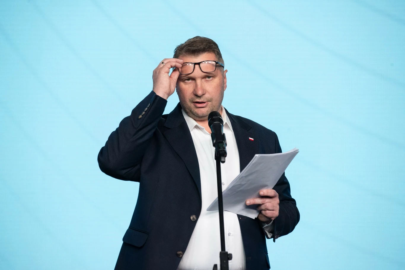 Przemysław Czarnek ma jedynie 15 tys. zł oszczędności - wynika z oświadczenia, jakie złożył w Sejmie Przemysław Czarnek z okularami na głowie, czarnej marynarce i bez krawata. Przemawia do mikrofonu. Trzyma dokumenty.