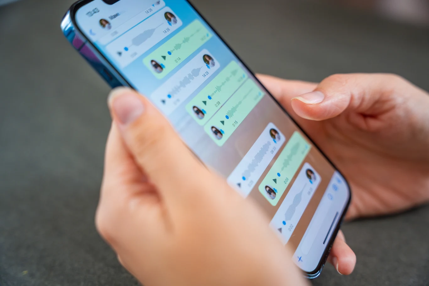 Oszuści często starają się przekierować rozmową na WhatsApp. To pułapka. Smartfon trzymany w dłoniach z aplikacją do czatowania na ekranie, wyświetlającą rozmowy tekstowe z różnymi kontaktami w profilach.