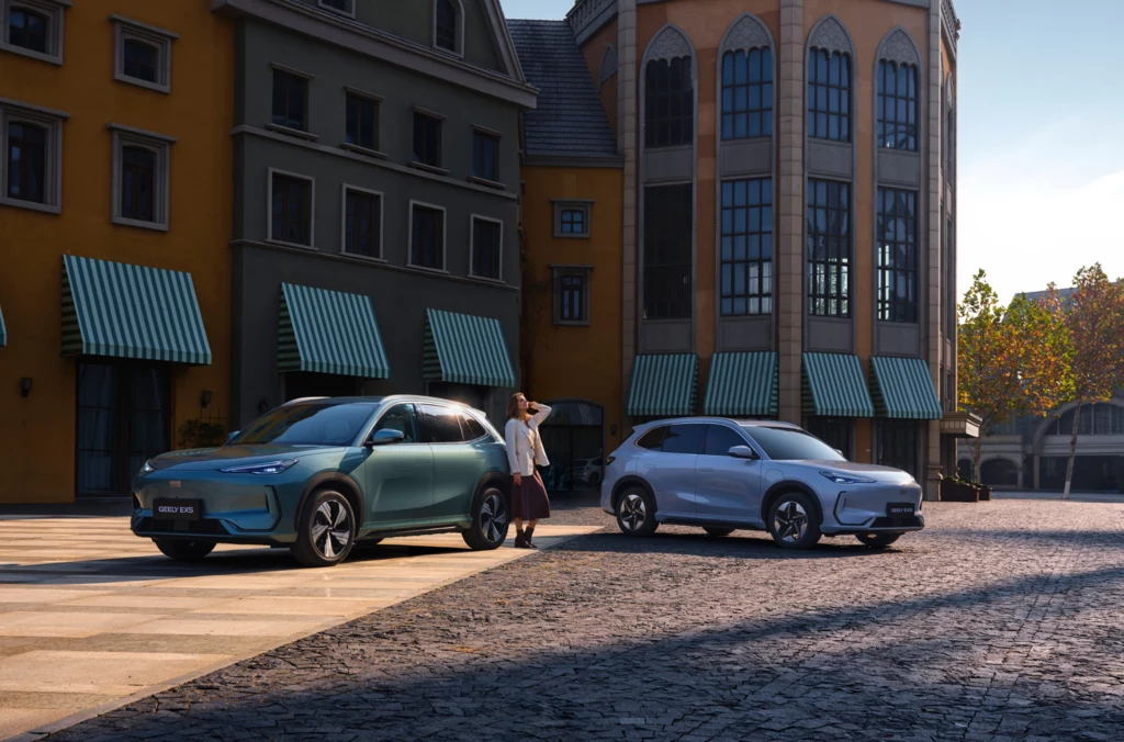 Geely Auto wprowadzi elektryczny SUV Geely EX5 oraz hybrydowy model plug-in w segmencie C-SUV. Dwa nowoczesne samochody zaparkowane przed stylowym budynkiem z zielonymi markizami, jeden z nich w kolorze turkusowym, drugi srebrnym. Na placu brukowanym stoi kobieta ubrana w jasny strój, patrząc w kierunku pojazdów.