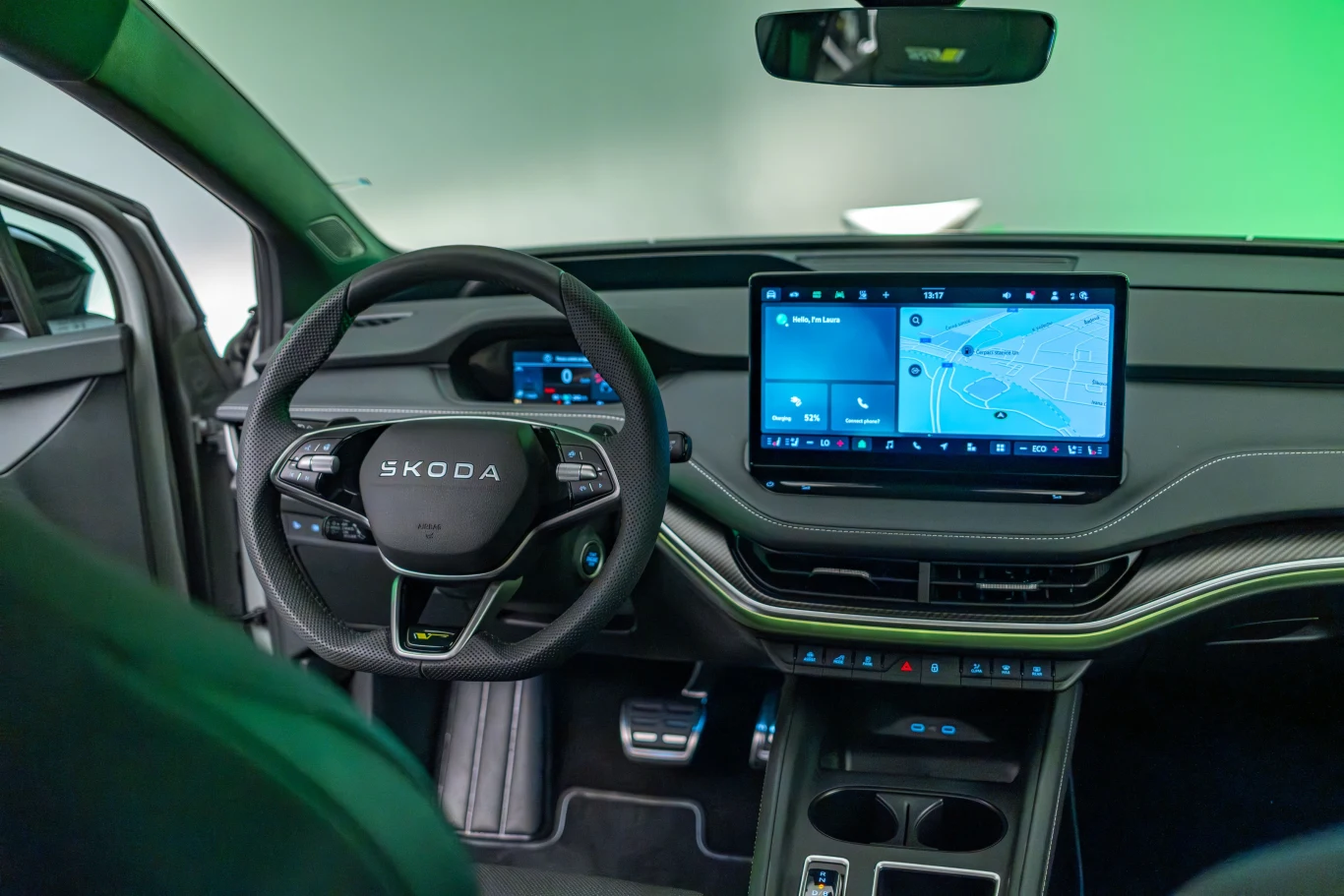 Wnętrze kabiny nowoczesnego samochodu Škoda z widocznym kierownicą, tablicą rozdzielczą i dużym ekranem wyświetlającym mapę nawigacji.