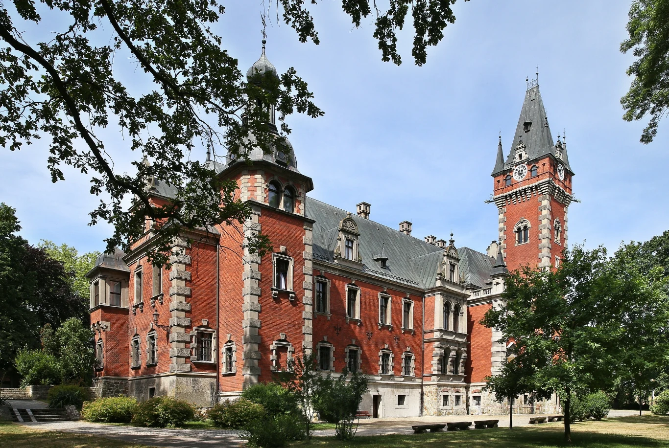 Pławniowice to prawdziwa śląska perełka. Na zdj. zabytkowy Pałac Ballestremów Ceglany pałac z wieżami, otoczony bujną zielenią, drzewa w pełnym rozkwicie wokół malowniczej budowli.