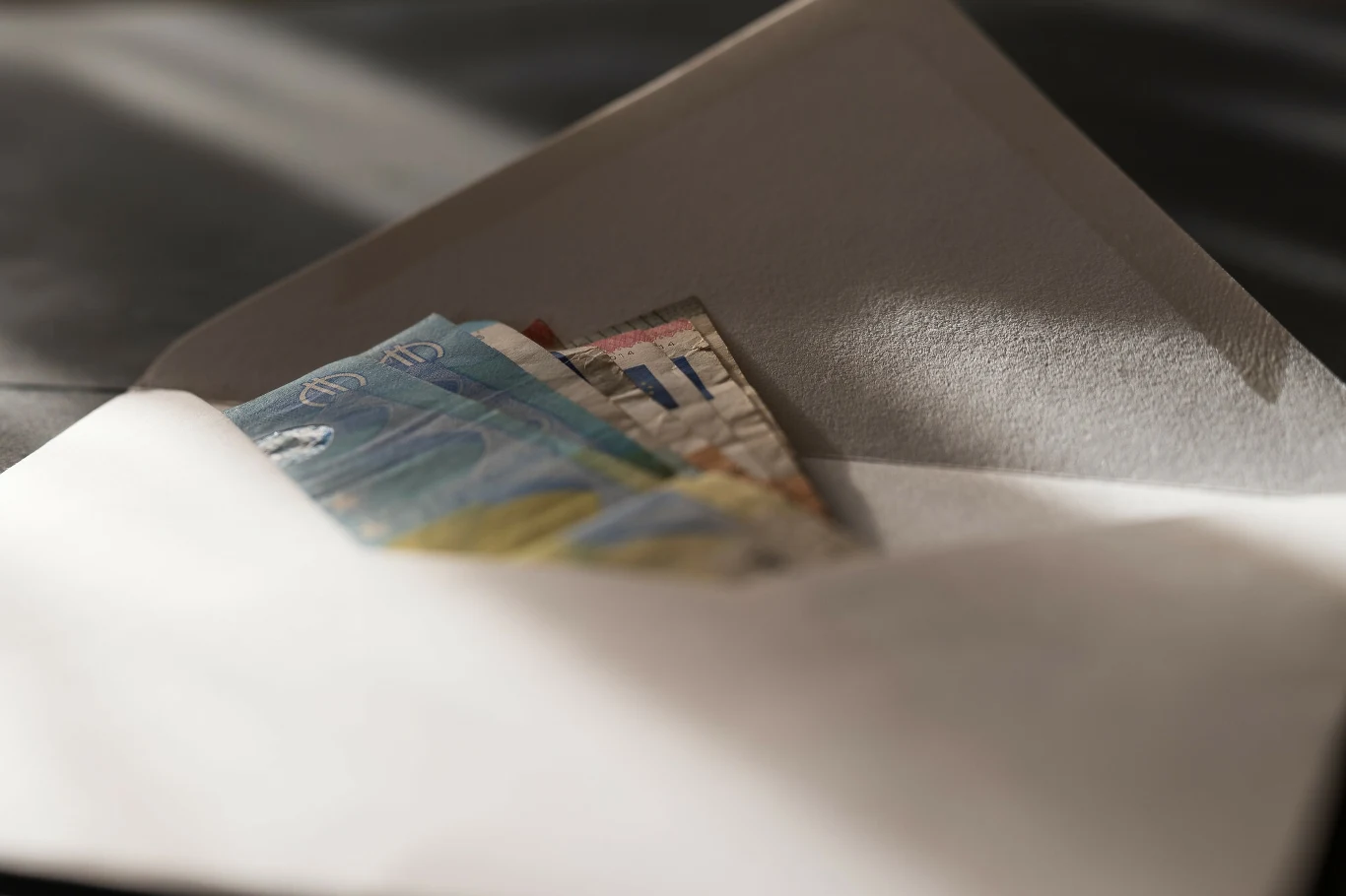 Tyle Włosi wkładają do koperty na wesele. To minimalna kwota Koperta z kilkoma wystającymi banknotami, oświetlona naturalnym światłem.