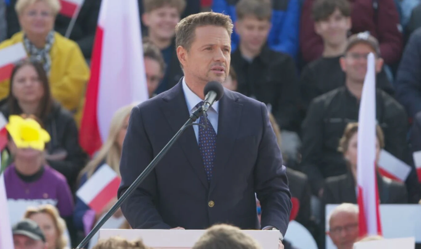 Wybory prezydenckie 2025. Wiec Rafała Trzaskowskiego w Bydgoszczy Mężczyzna w garniturze przemawia do mikrofonu, stojąc na scenie przed tłumem ludzi trzymających polskie flagi.