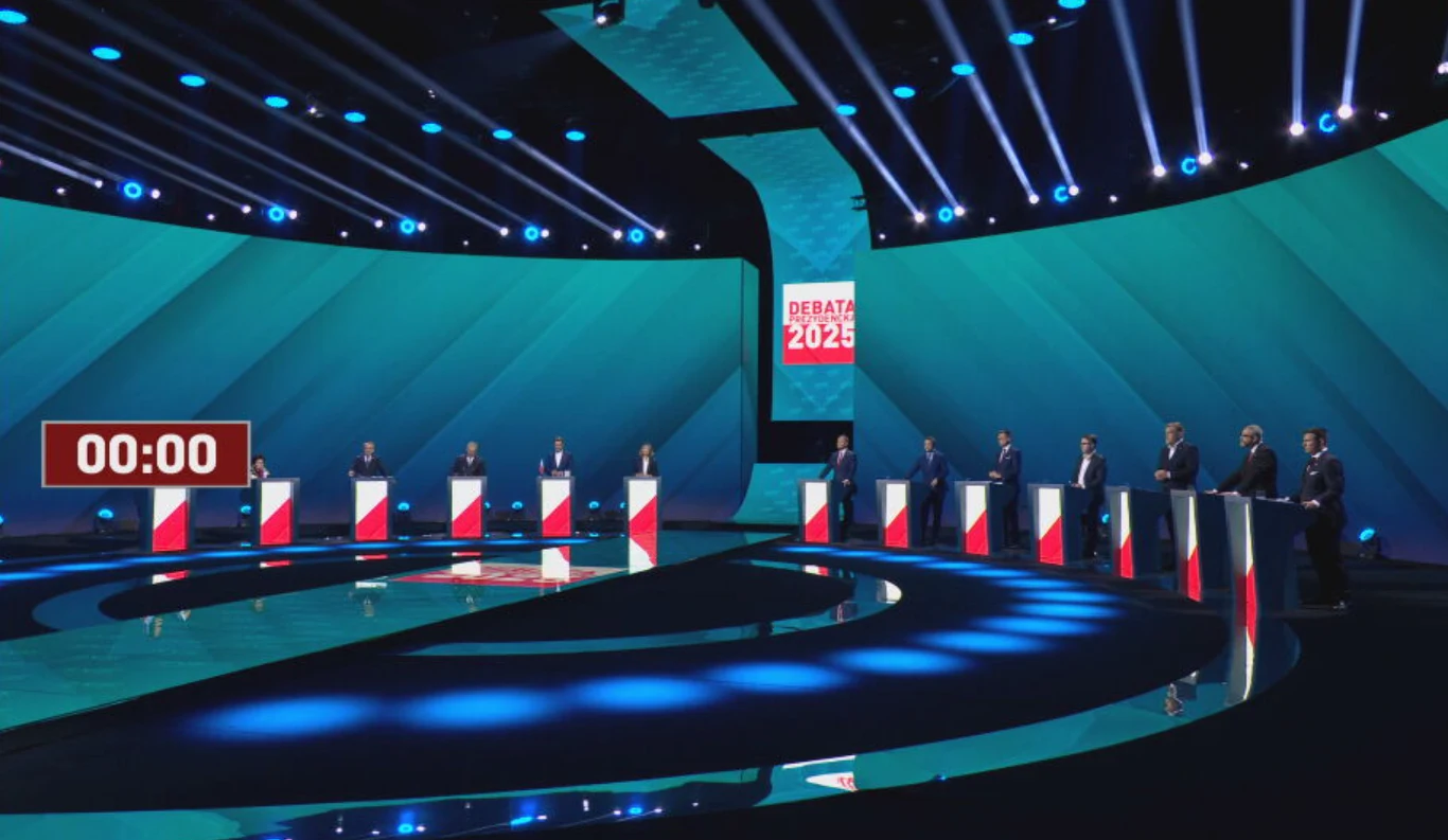 Kandydaci na prezydenta zabrali głos w sprawie wojny w Ukrainie Scena debaty politycznej z równo ustawionymi pulpitami, każdy ozdobiony narodową flagą. Wyposażenie oświetleniowe i cyfrowy licznik czasu umieszczony po lewej. W tle ekran z napisem 'Debata 2023'.