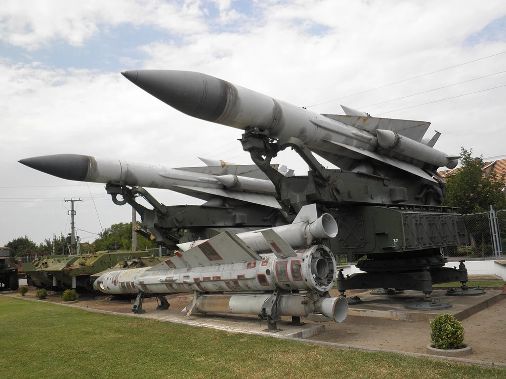 Wyrzutnie i pociski systemu S-200 Wega Rakiety wojskowe ustawione na zewnętrznej ekspozycji, prawdopodobnie jako część muzeum lub wystawy militarnej. Rakiety są duże, z wyróżniającymi się aerodynamicznymi kształtami, umieszczone są na specjalnych platformach.