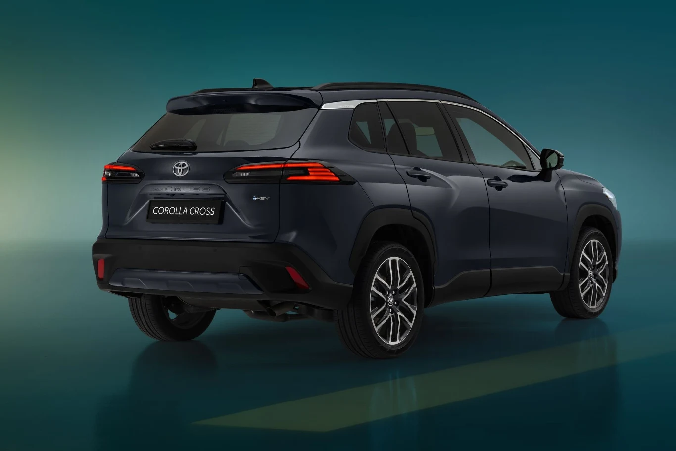 Tylny widok samochodu Toyota Corolla Cross w eleganckim ciemnym kolorze, wyróżniający się nowoczesnym designem i charakterystycznymi lampami tylnymi na tle gradientowego zielono-niebieskiego tła.