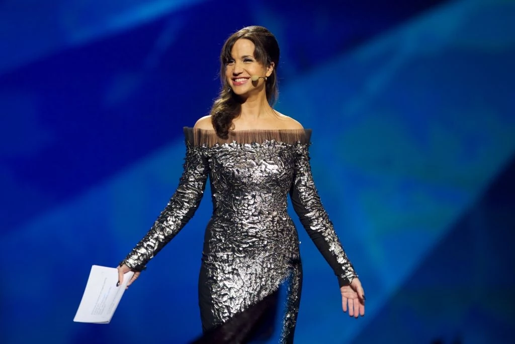 Uważana za najlepszą prowadzącą w historii Eurowizji, Szwedka Petra Mede pojawiła się Bazylei Elegancko ubrana kobieta w srebrnej, połyskującej sukience, trzyma kartki. Jest na scenie, uśmiecha się i patrzy w stronę publiczności, mikrofon przyczepiony do twarzy. To Petra Mede