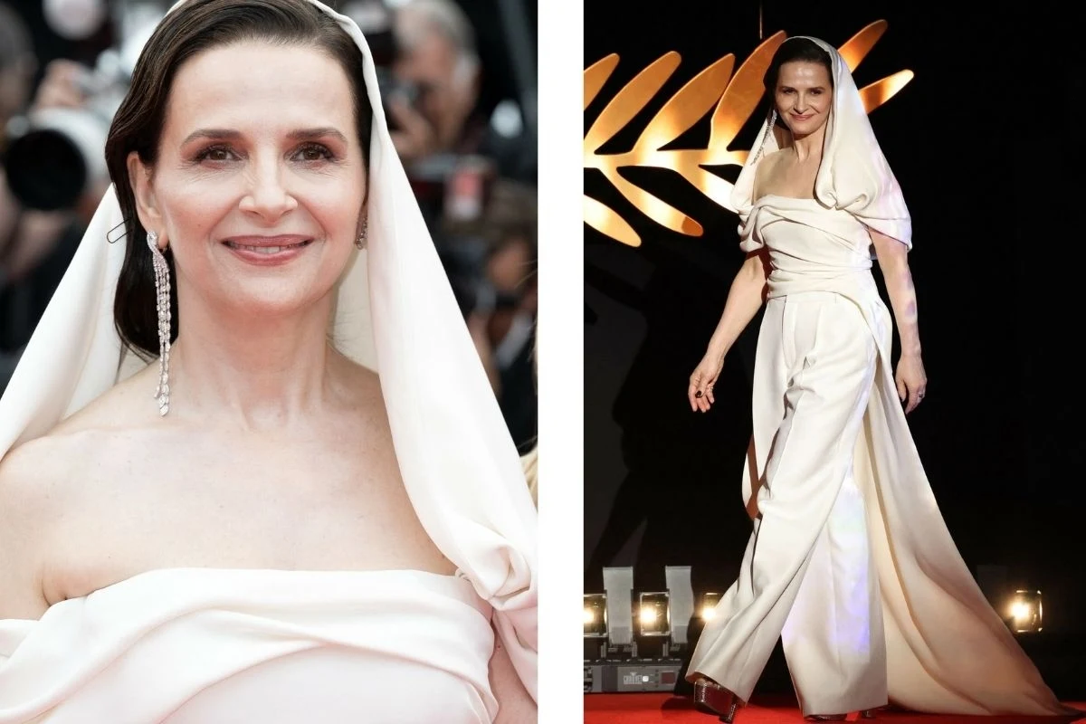 Juliette Binoche na 78. Międzynarodowym Festiwalu Filmowym w Cannes Juliette Binoche ubrana w białą, elegancką bluzkę z kapturem i szerokie spodnie imitujące spódnicę. Nosi długie kolczyki. Idzie po czerwonym dywanie. Wygląda na pewną siebie i uśmiechniętą.