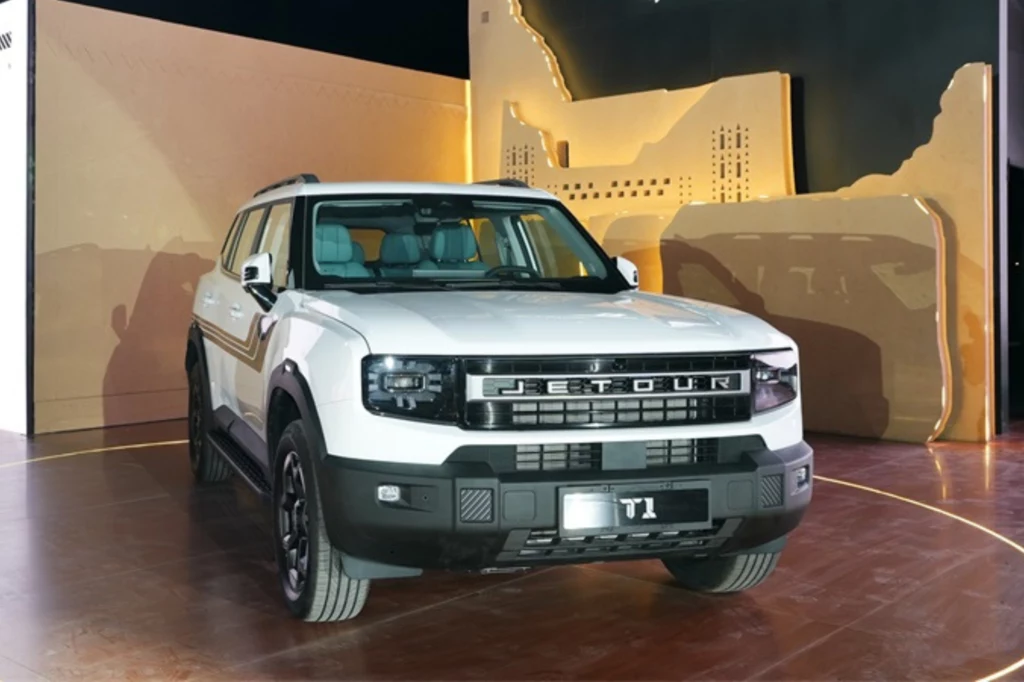 Model T1 podbija Katar i Zjednoczone Emiraty Arabskie Biały samochód terenowy Jetour T1 stoi na wystawie, otoczony eleganckim, nowoczesnym wnętrzem. Charakterystyczny grill z dużym napisem "Jetour" oraz stylowe reflektory dodają mu wyrazistości.