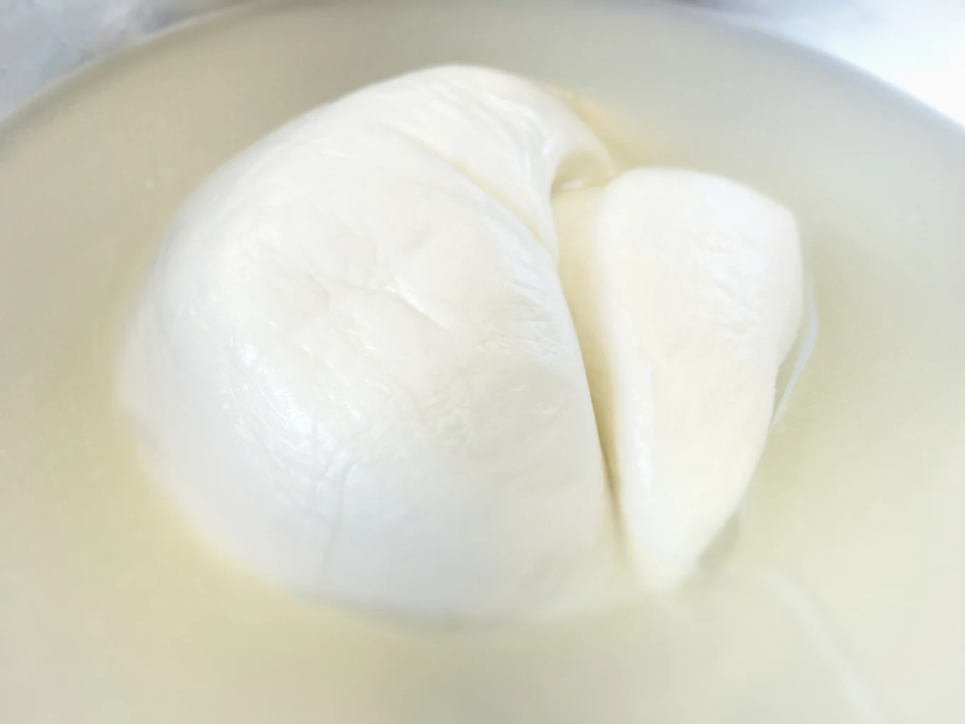 Mozzarella to prawdziwy rarytas. Istnieje jednak jej inna, jeszcze smaczniejsza odmiana Biała kula sera mozzarella zanurzona w płynie, częściowo przecięta. Powierzchnia sera jest gładka i błyszcząca, płyn ma mleczny kolor.