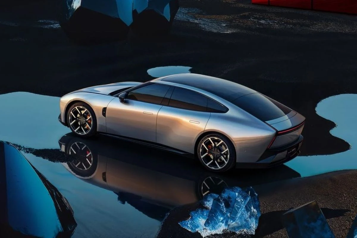 Srebrny, nowoczesny samochód sportowy zaparkowany na ciemnej nawierzchni, odbijający się w kałużach wody. Wokół znajdują się niebieskie, abstrakcyjne formy, które wprowadzają futurystyczny klimat.