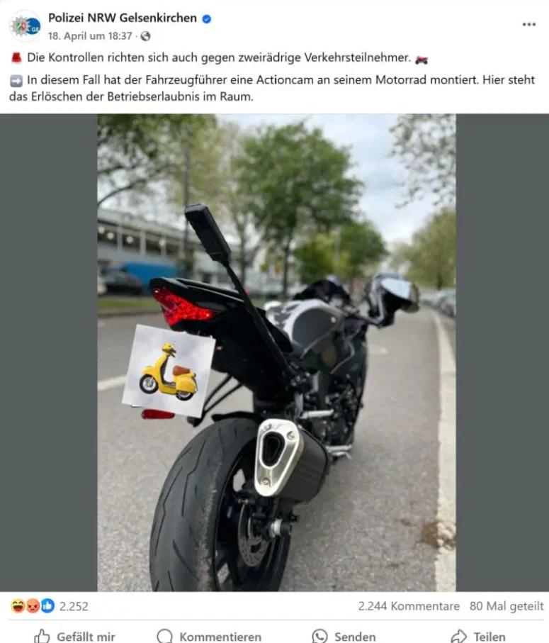 Chociaż montaż kamery nie był zmianą konstrukcyjną, demontaż teleskopu wymagał użycia narzędzi. / Fot. Facebook Polizei NRW Gelsenkirchen Motocykl zaparkowany na ulicy, na której widoczne są drzewa i inne zaparkowane pojazdy. Z tyłu motocykla zamontowana jest kamerka. Zdjęcie ma charakter edukacyjny, informuje o kontrolach drogowych.