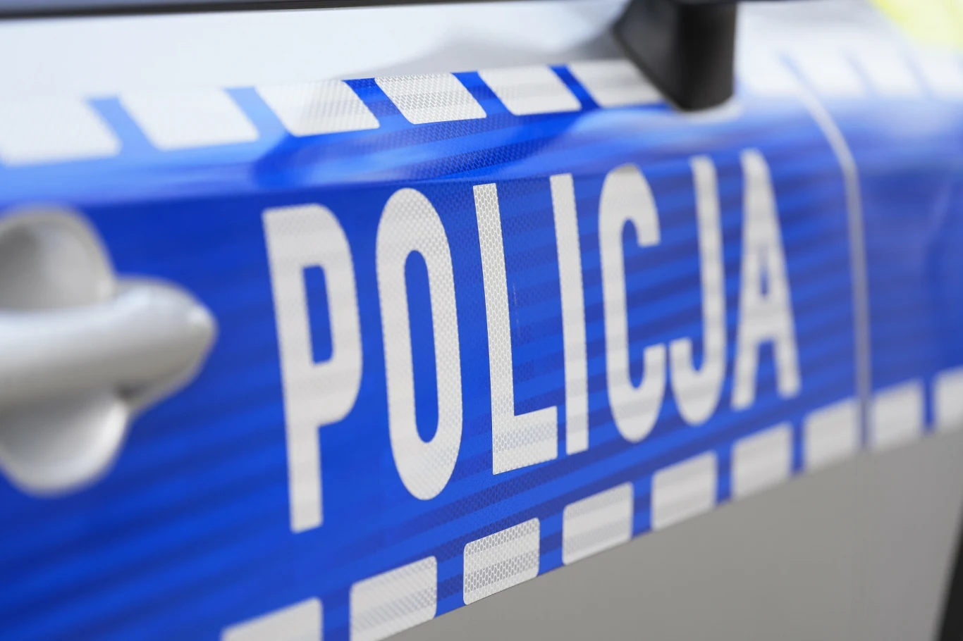 Policja bada doniesienia o możliwej strzelaninie w Krakowie Napis 'Policja' na boku pojazdu policyjnego w kolorze niebieskim z białymi literami.