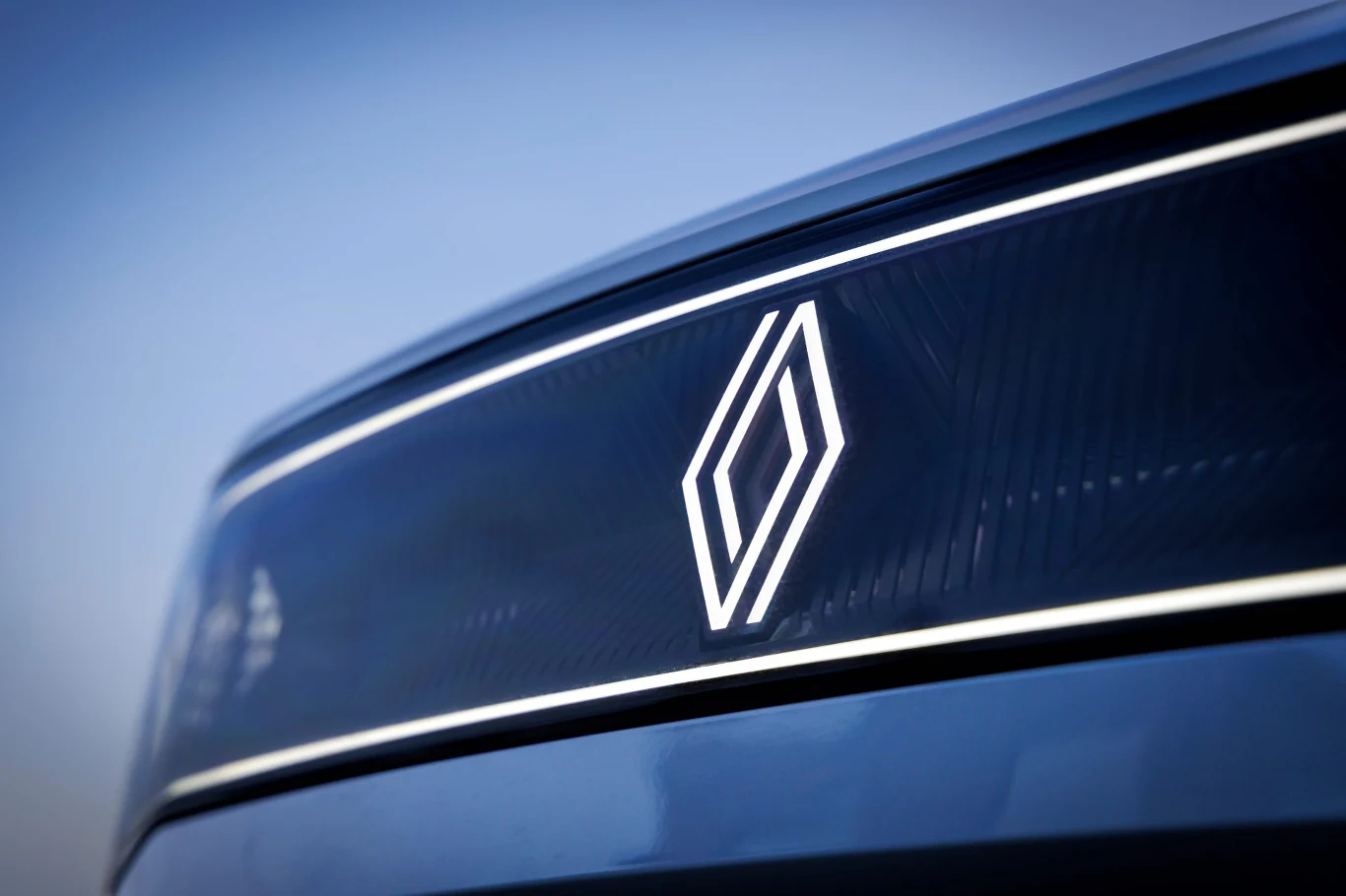Renault planuje zwolnienia. Pracę straci 2,4 tys. inżynierów. Logo Renault na tle siedziby firmy z podpisem o planowanych zwolnieniach 2,4 tys. inżynierów.