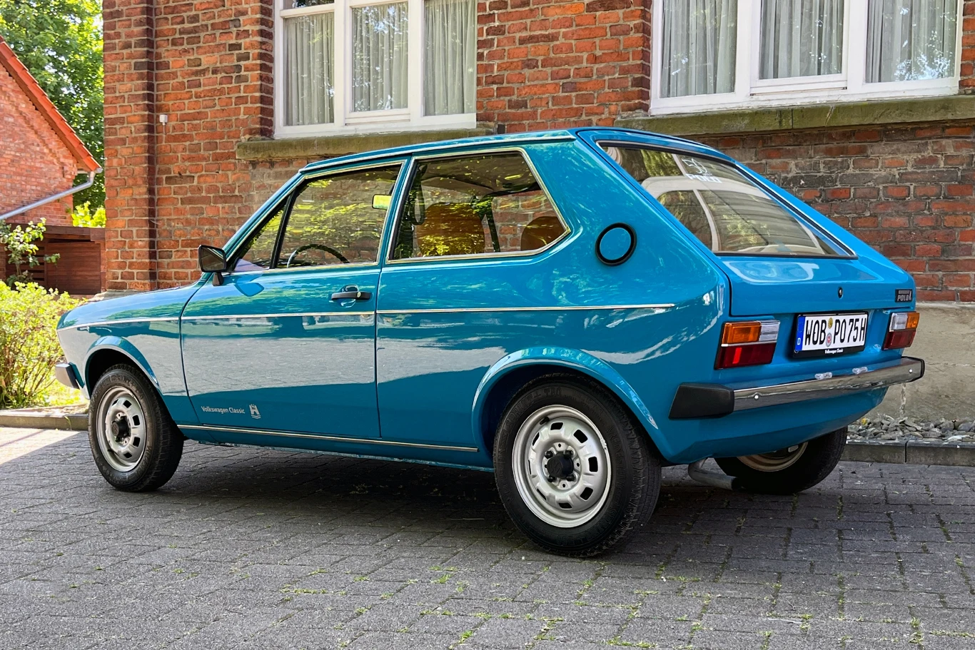 Samochód oferował miejsce dla czterech pasażerów oraz bagażu. Niebieski samochód typu hatchback stoi zaparkowany na brukowanej drodze przed ceglaną ścianą budynku. Pojazd ma prosty, klasyczny design z lat 70., z dużymi oknami i charakterystycznym tyłem.