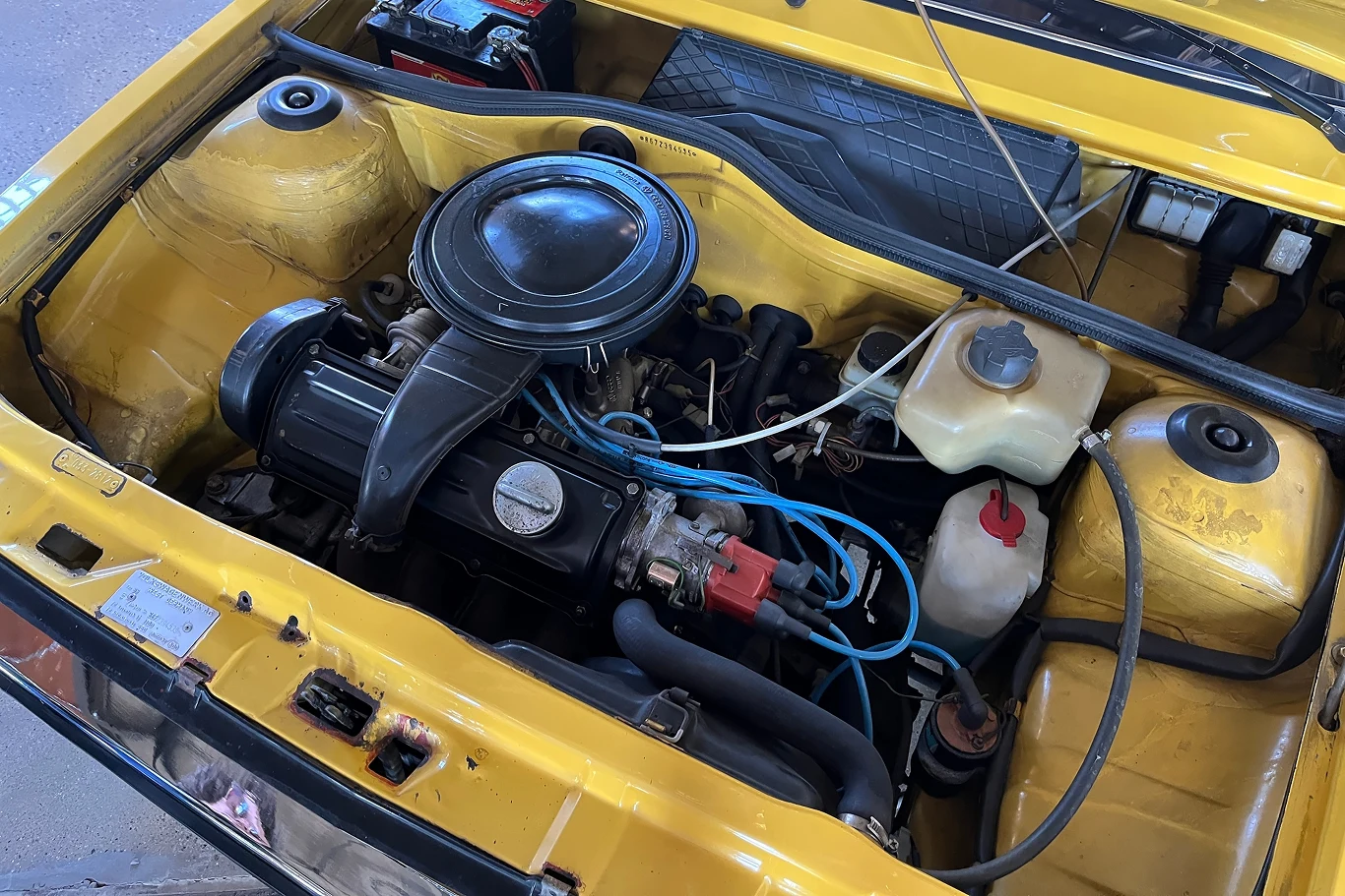 W podstawowej wersji Polo dysponowało mocą 40 KM. Komora silnika żółtego samochodu z odsłoniętym silnikiem, akumulatorem i innymi elementami mechanicznymi.