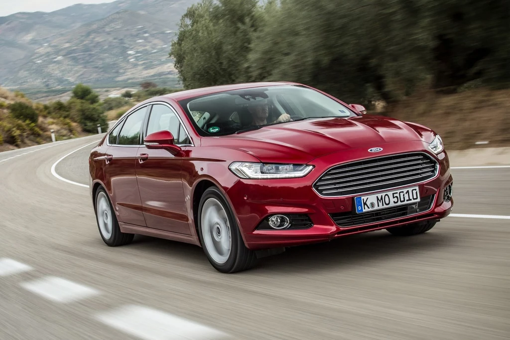 Słowacka drogówka korzysta m.in. z nieoznakowanych Fordów Mondeo i to nierzadko w najmocniejszych wersjach. Czerwony samochód marki Ford Mondeo z niemieckimi tablicami rejestracyjnymi, jadący po zakrętej, asfaltowej drodze na tle górzystego krajobrazu.