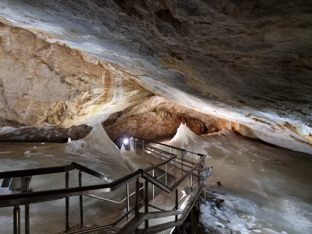 Lodowa jaskinia została wpisana na listę UNESCO Jaskinia z metalowym podestem prowadzącym przez lodowe formacje. Stalagmity i stalaktyty pokryte lodem, tworząc fascynujący krajobraz podziemny. Oświetlenie punktowe podkreśla naturalne piękno jaskini.