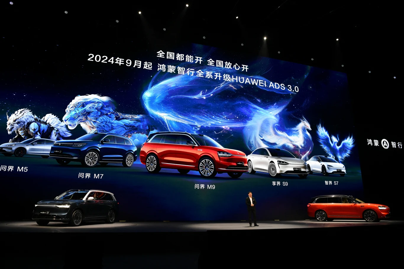 Moderna scena przedstawiająca prezentację nowych modeli samochodów na dużym ekranie. Światła oświetlają pojazdy, a wokół nich znajdują się efekty świetlne w kształcie mitycznych zwierząt. Na ekranie widoczne są nazwy i numery modeli oraz informacje o a...