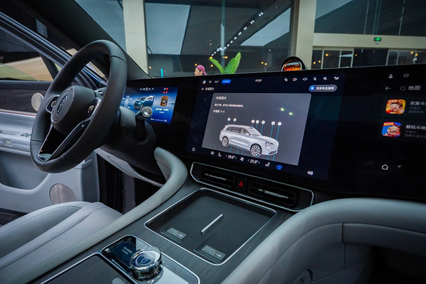 Widok na nowoczesne wnętrze samochodu elektrycznego z dużym wyświetlaczem na desce rozdzielczej. Ekrany prezentują interfejs systemu oraz schematyczny obraz pojazdu, co podkreśla zaawansowaną technologię i funkcjonalność. Kierownica oraz konsola środko...